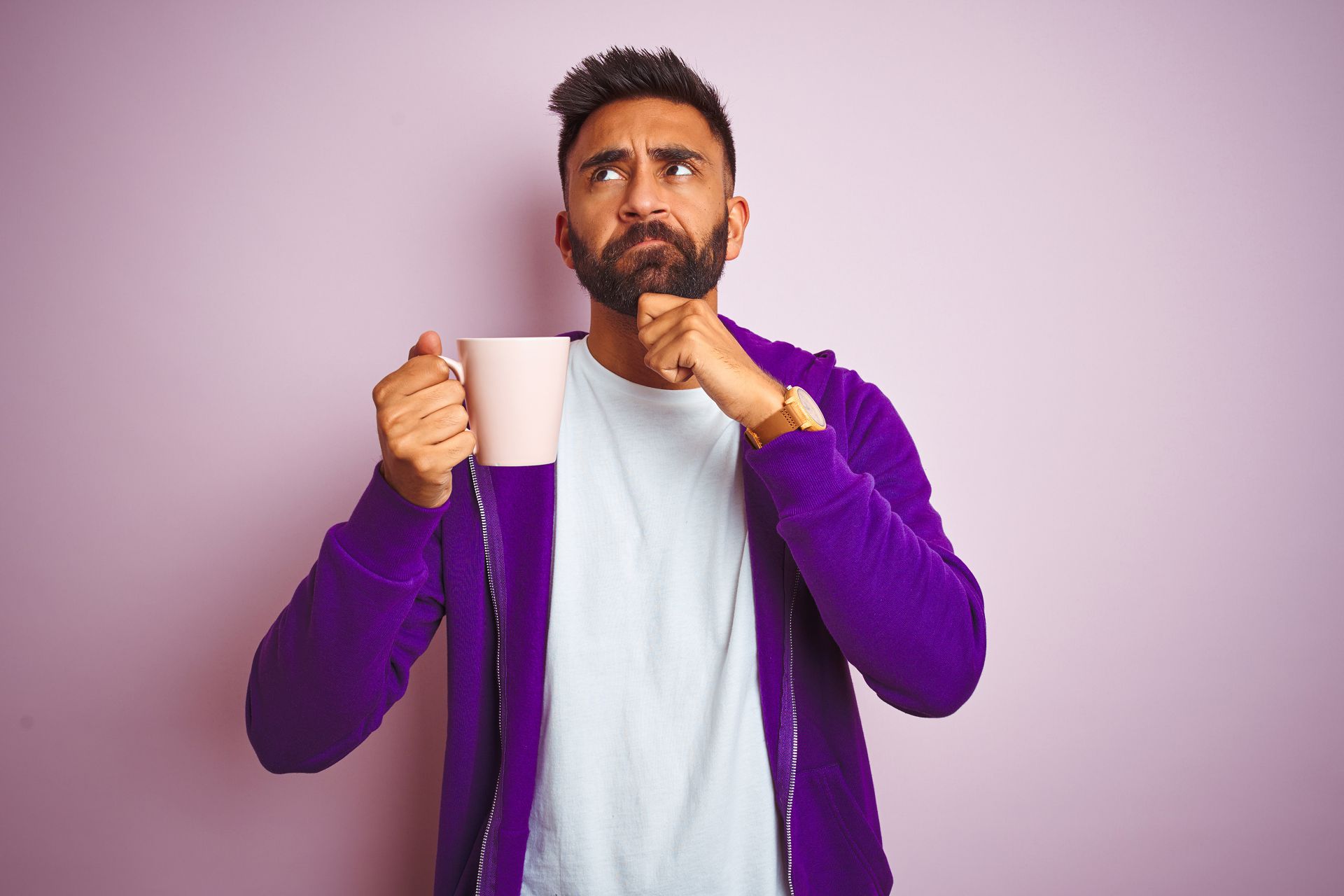 Indian man wearing purple sweatshirt drinking cup of coffee over isolated pink background serious face thinking about question, very confused idea Actualités MONO-France